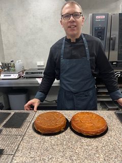 Pâtissier posant devant deux gâteaux